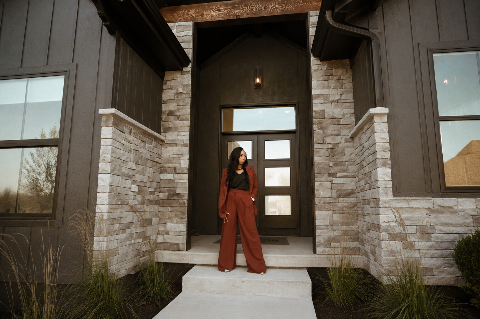 Ericka standing at the front entrance of a modern Kansas City home at dusk